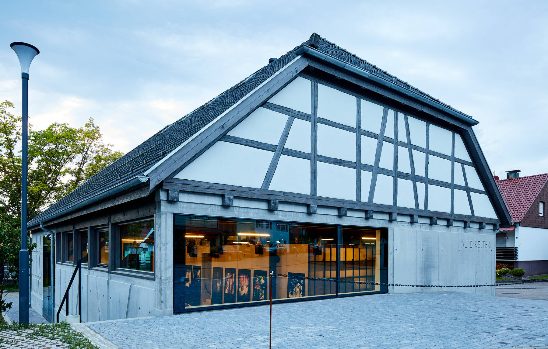 Ansicht der Alten Kelter mit saniertem Fachwerk und moderner Isolar Glasfassade im Erdgeschoss.