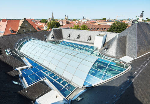 Außenansicht des Historischen Museums der Pfalz in Speyer, bei der sich die moderne Glasarchitektur harmonisch in die historische Bausubstanz einfügt.